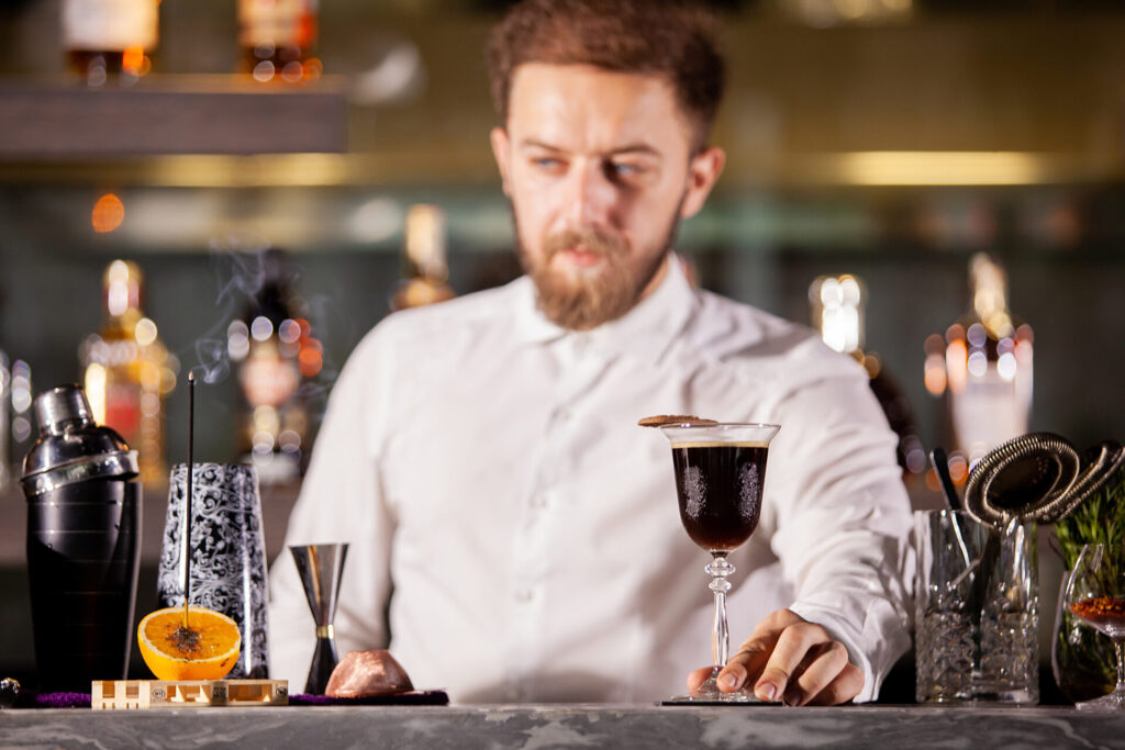 Bartenderpresenting coffe cocktail in lounge bar. Good atmosphere